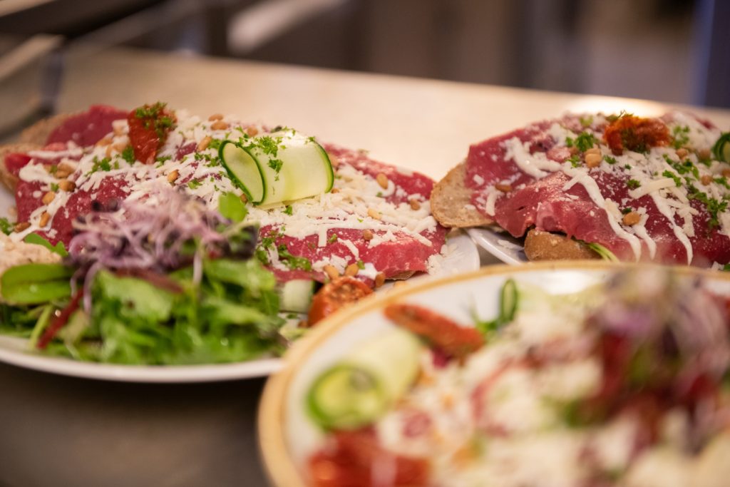 Carpaccio met kaas en salade op een bord.